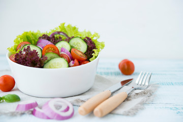 Summer vegetable salad with seasonal vegetables on rustic wooden background.
