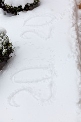 2020 written on white snow. Snow lies on paving slabs