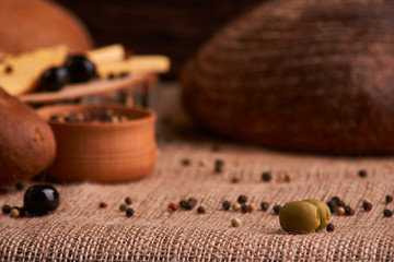 olive is on the table in background of bread, baguette and cheese. Selective focus