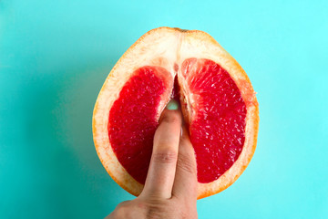 Fototapeta two fingers in a grapefruit isolated on a blue background top view sex concept obraz