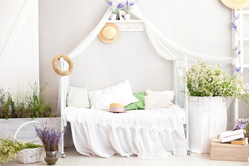 Shabby white chic bedroom interior for a country house. Lavender in a vase, a barrel of daisies and...