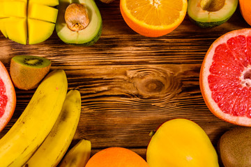 Still life with exotic fruits. Bananas, mango, oranges, avocado, grapefruit and kiwi fruits on wooden table. Top view