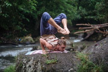 Yoga practice and meditation in nature. Man practicing near river