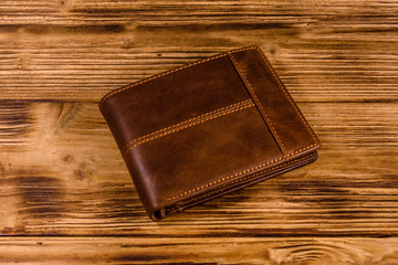 Closed brown leather wallet on wooden table