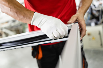 Obraz premium Manual worker assembling PVC doors and windows. Manufacturing jobs. Selective focus. Factory for aluminum and PVC windows and doors production.