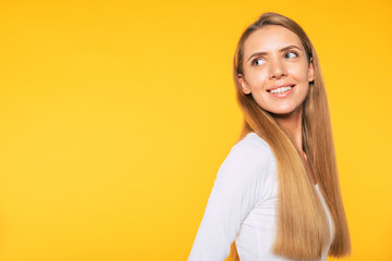 Beautiful blonde young woman in casual white wear is posing over colorful wall. Beauty and fashion concept. Blonde student girl.