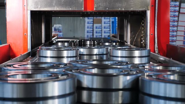 Industrial and machinery concept. A tecnological part of bearing production and assembling. Conveyor in bearing factory. Ready items are being poured with engine oil in moving technology line. close