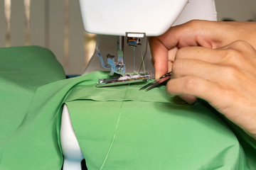 Woman tailor sews fabric on a sewing machine in the workshop. Close-up. Copy space