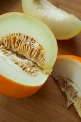 sweet ripe yellow melon cut into slices with seeds on a wooden