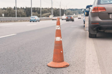 Attention traffic cone on the road. Selective focus. Tow truck towing a broken down car on the highway