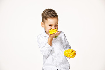 handsome boy in a white shirt is eating a mango