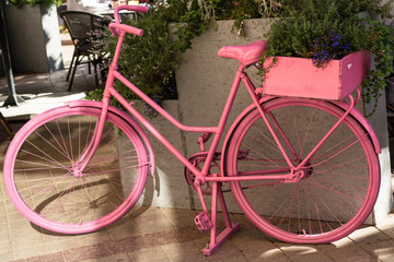 Fototapeta na wymiar Decorative, vintage bike, painted in pink paint stands in the city