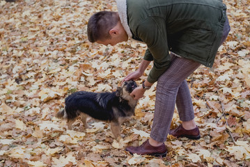 Young man playing with funny dog in autumn park. Save animals