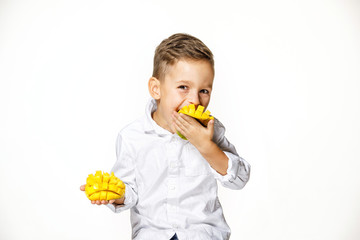 handsome boy in a white shirt is eating a mango