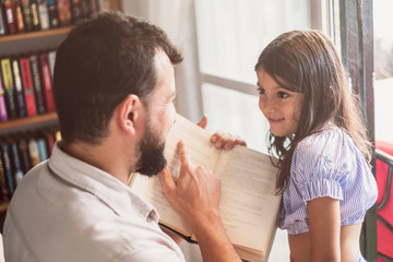 father and daughter learning how to read at home