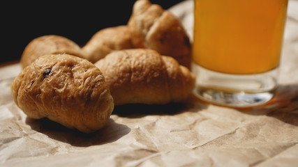 Freshly baked croissants with orange juice on kraft paper. Closeup photography of fresh delicious dessert for breakfast.