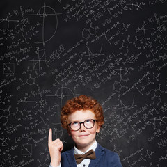 Smart child boy with curly ginger hair in glasses. Genius kid portrait