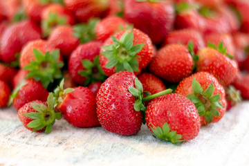 Lots of fresh ripe red strawberries on the white table. Home garden harvesting