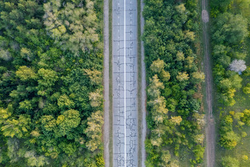 Aerial view of a of an empty abandoned road in the forest. Beautiful landscape with empty rural road. Top view from flying drone. Flat lay. Nature