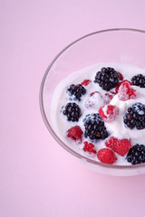 Ice cream with raspberry, blackberry berries in glass bowl on pink background