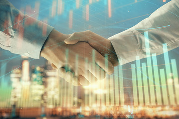 Double exposure of financial chart on cityscape background with two businessmen handshake. Concept of financial analysis and investment opportunities