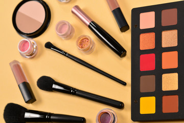 Professional makeup products with cosmetic beauty products, eye shadows, pigments, lipsticks, brushes and tools on beige background. Space for text or design.