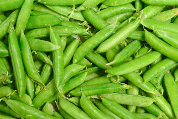 Fresh pea pods as background. Top view.