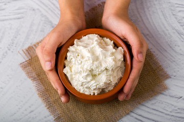Homemade white butter - Girl hands holding a clay bowl with freshly prepared white butter in home