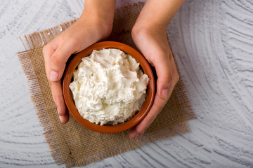 Homemade white butter - Girl hands holding a clay bowl with freshly prepared white butter in home