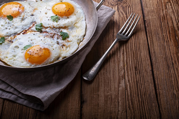 Fried eggs on white wooden background