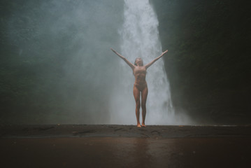 Naklejka na ściany i meble Beautiful girl having fun at the waterfalls in Bali. Concept about wanderlust traveling and wilderness culture