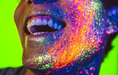 Handsome boy dancing at the rave party with fluorescent paintings on his face
