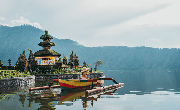 Beautiful girl kayaking on the catamaran at the ulun datu pura bratan temple, in Bali