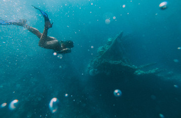 Discovering a japanese ship wreck from second world war. Beautiful woman swimming underwater in a...