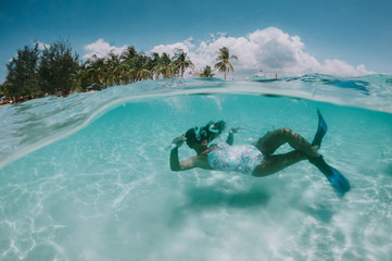 Beautiful woman swimming underwater in a tropical sea full of corals. under water shot with action...