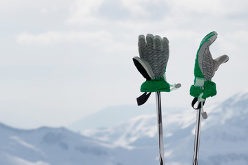 Gloves on ski poles and snowy winter mountain
