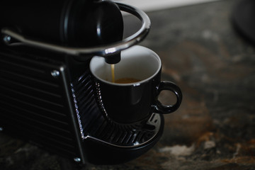 Black coffee machine pouring espresso into cup. 