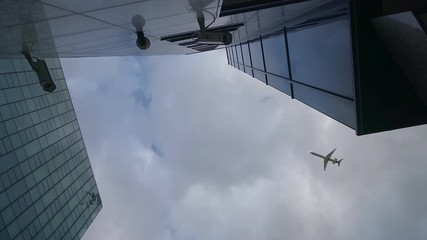 Airplane flying over skyscrapers and reflects in glass modern facades, Germany