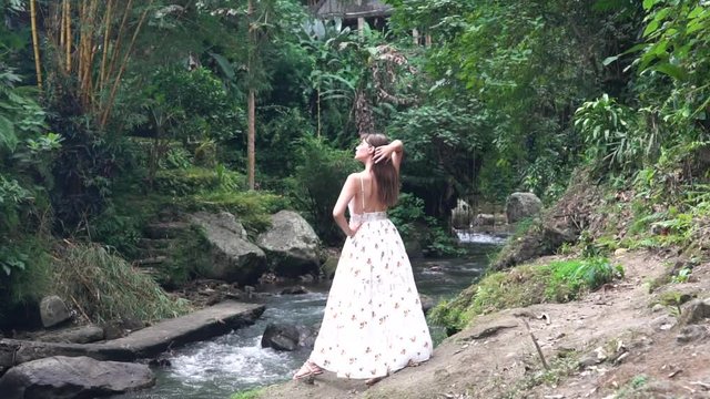 Beautiful girl model in white dress in the jungle near the waterfall.