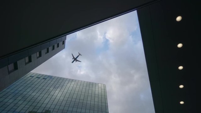 Airplane flying over skyscrapers and reflects in glass modern facades, Germany
