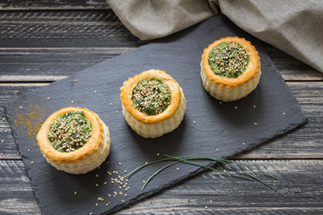 Three puff pastry containers filled with spinach puree with sesame seeds