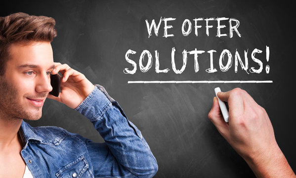 We Offer Solutions concept from analyst, consultancy or advisor with a businessman writing the words in chalk on a blackboard conceptual of problem solving 
