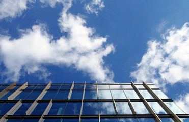 Fototapeta na wymiar modern office building with mirrored glass windows reflecting a bright blue sky and white clouds