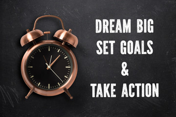 alarm clock with motivational message on blackboard