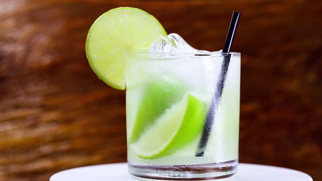 Typical drink from Brazil called Caipirinha, made with lemon and sugar with cacha&ccedil;a. Favorite cocktail of Brazil, isolated over wood texture.