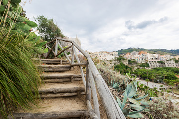 Fototapeta na wymiar Wooden stairs way on a green garden in Italy, Tropea
