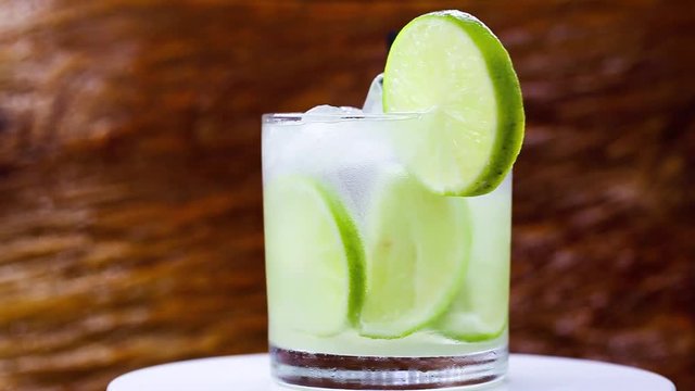 Typical drink from Brazil called Caipirinha, made with lemon and sugar with cacha&ccedil;a. Favorite cocktail of Brazil, isolated over wood texture.