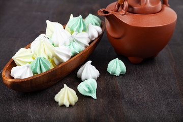 Meringue in a wooden bowl and brown teapot