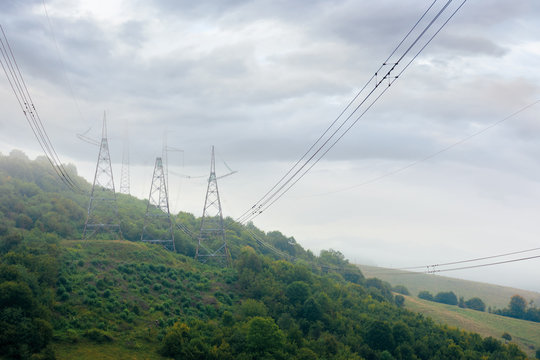 high voltage power lines tower in mountains.  energy delivery background. efficient electricity delivery concept. hazy weather with overcast sky