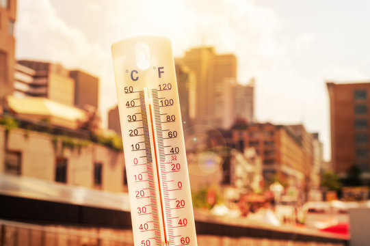 Thermometer in front of an urban scene during heatwave